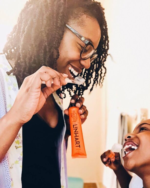 Woman and child laughing while brushing teeth with Linart toothpaste.