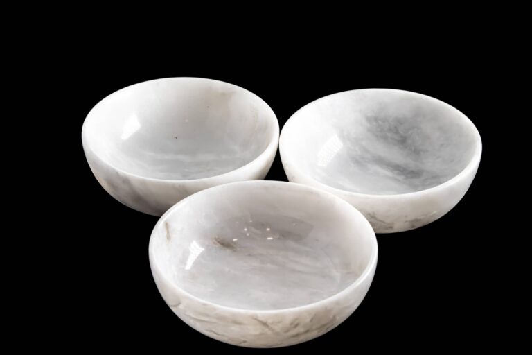 Three white marble bowls with gray veining on a black background.